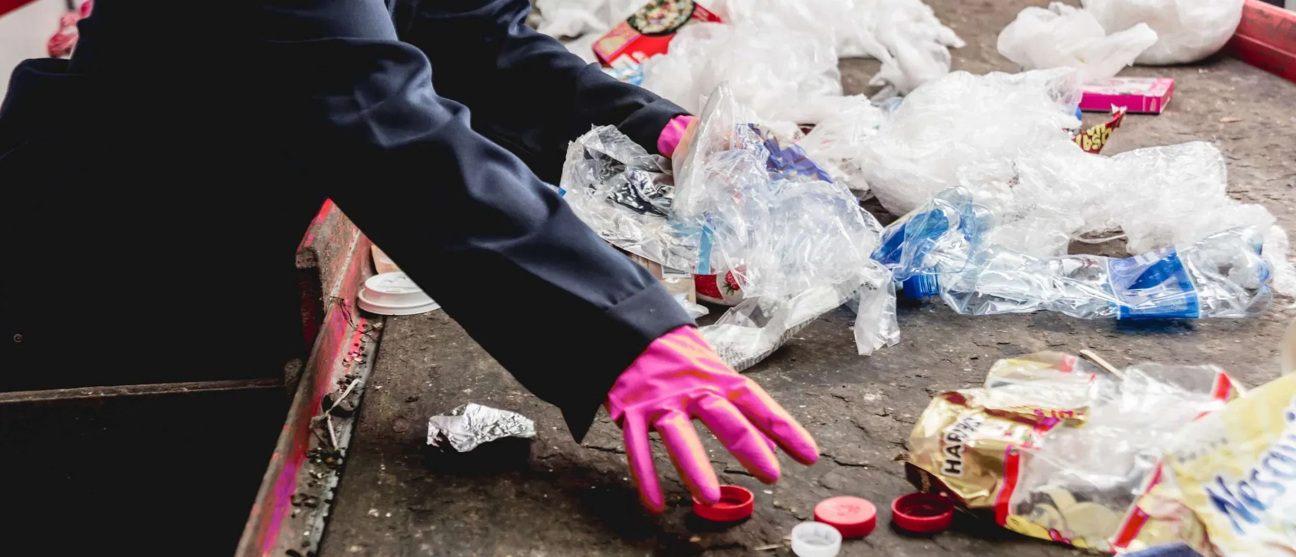 Worker sorting post-consumer plastic waste in an Australian recycling facility
