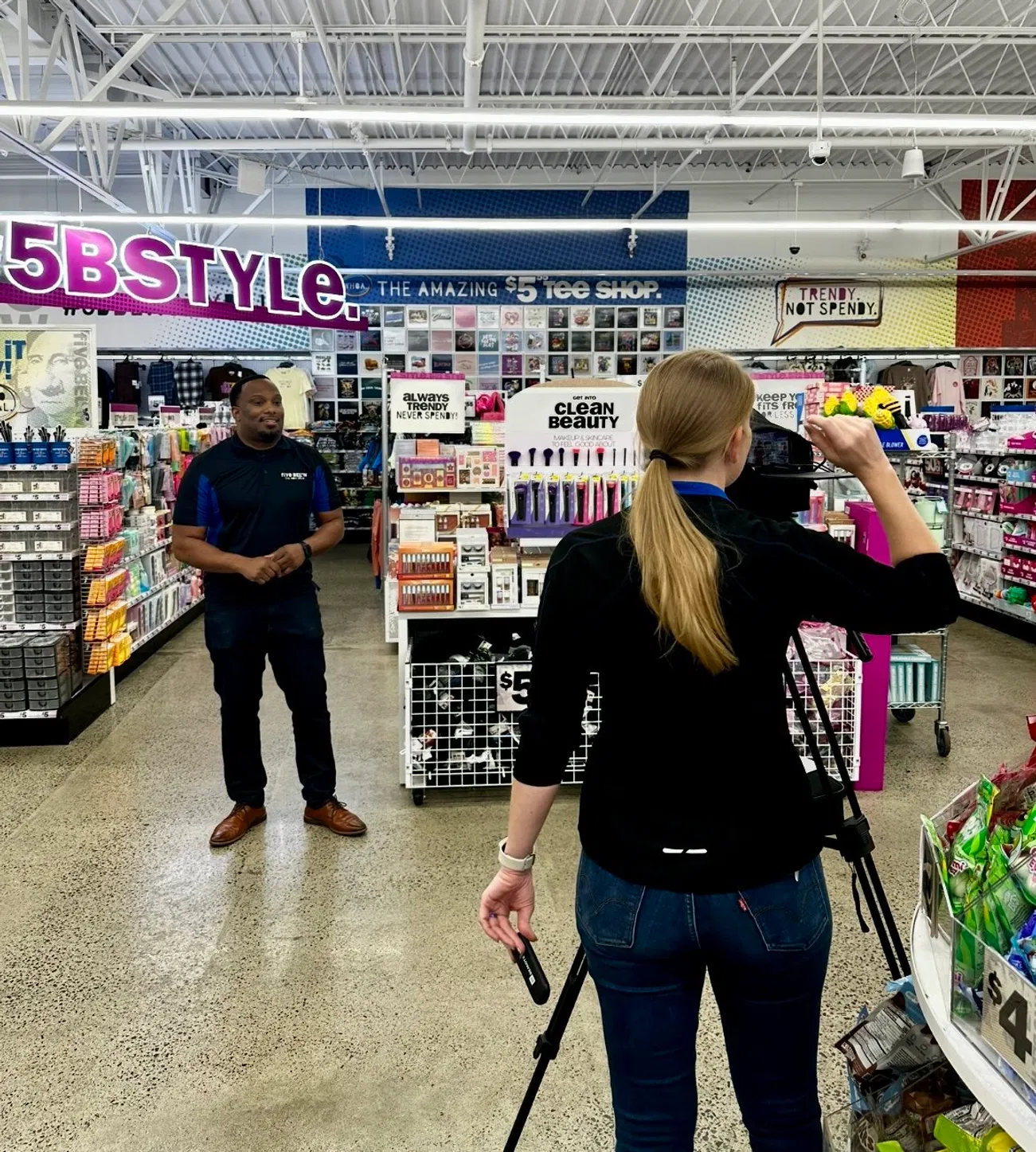 A videographer from Blue Plate Production captures a real-world loss prevention scenario in a retail store aisle, highlighting authentic training content creation.