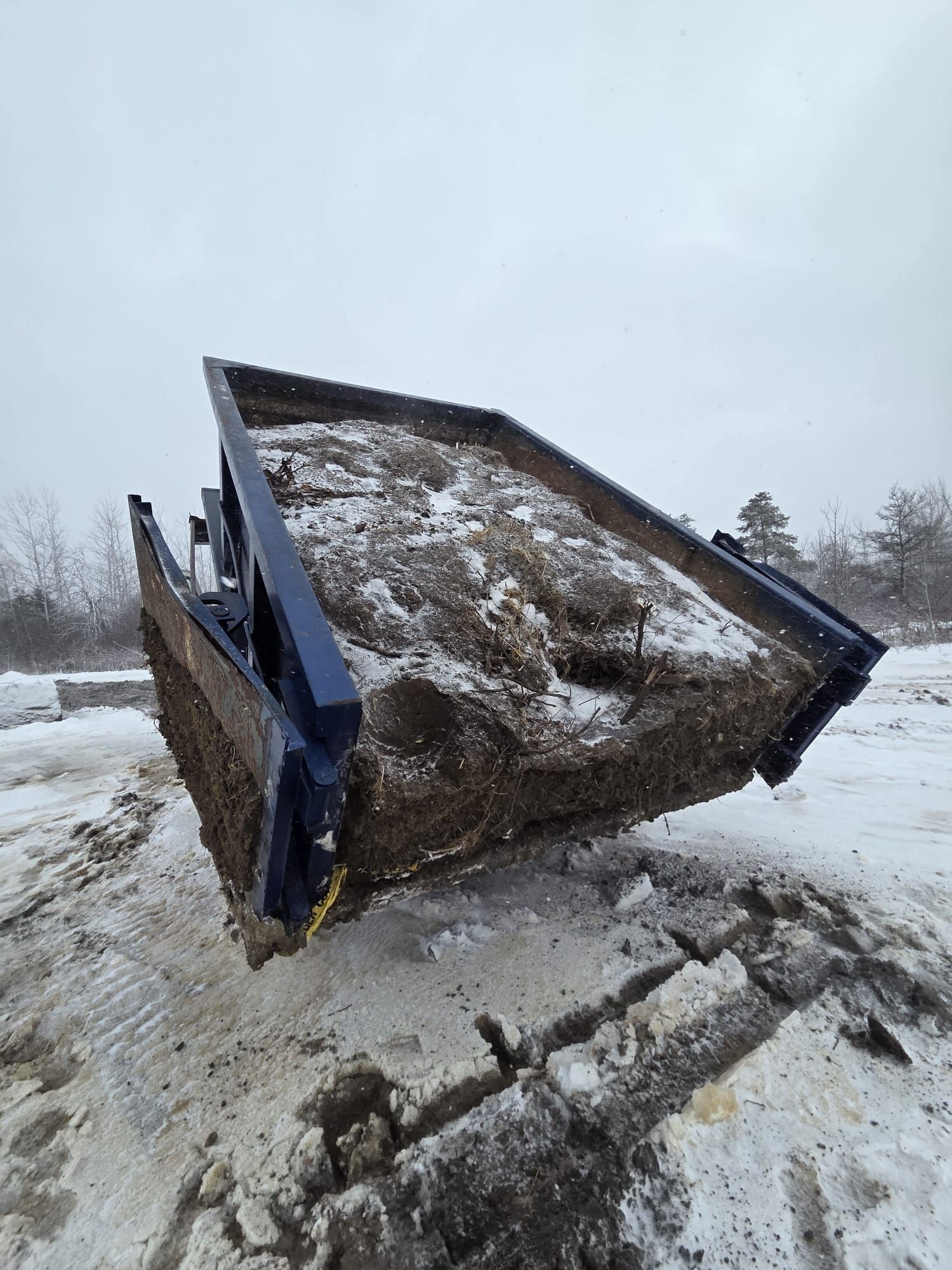 Managing Heavy Construction Debris: 4-Yard vs 10-Yard Bins in North York A large roll-off dumpster is tipped to unload a full load of soil and debris in snowy conditions.