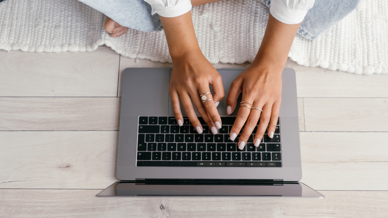 Person using a laptop on a light wooden floor