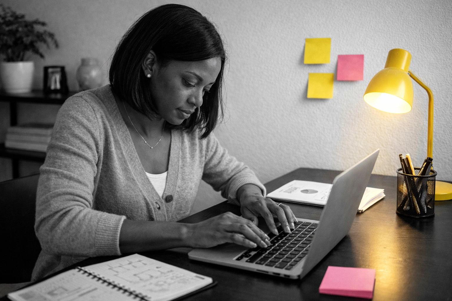 Black woman entrepreneur focused on work in a quiet workspace, building her business in the background