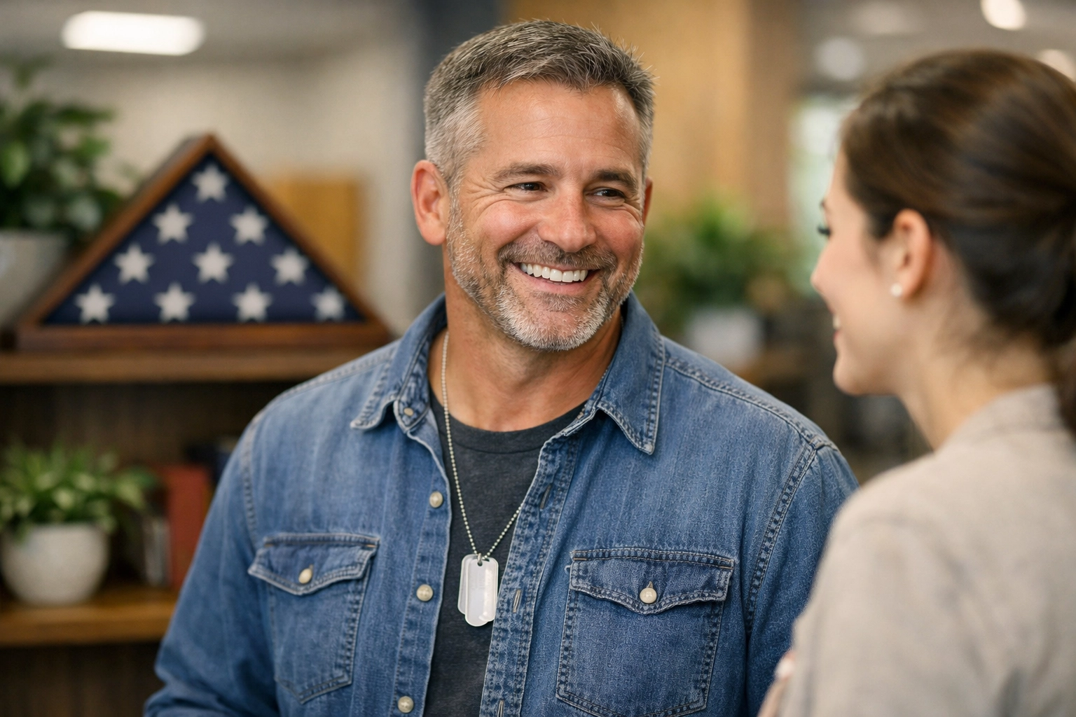 A military veteran discussing community support initiatives next to a memorial American flag shadow box.