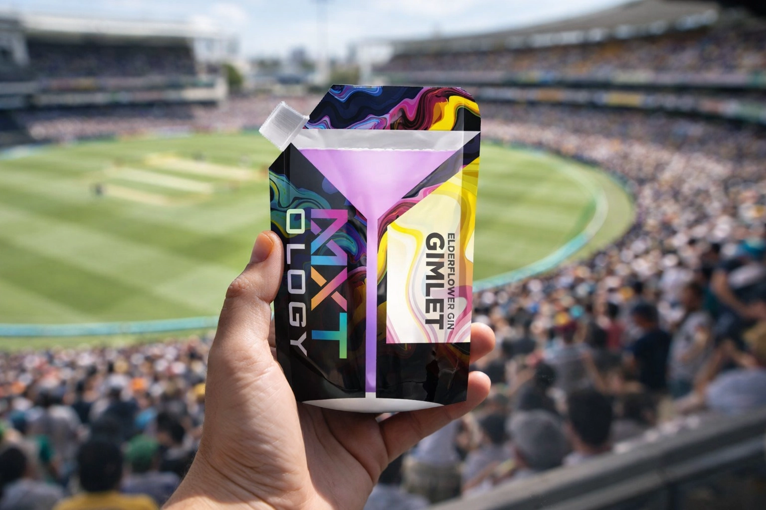 A refreshing lime-green cocktail pouch held at a sun-lit cricket ground with a large stadium crowd.