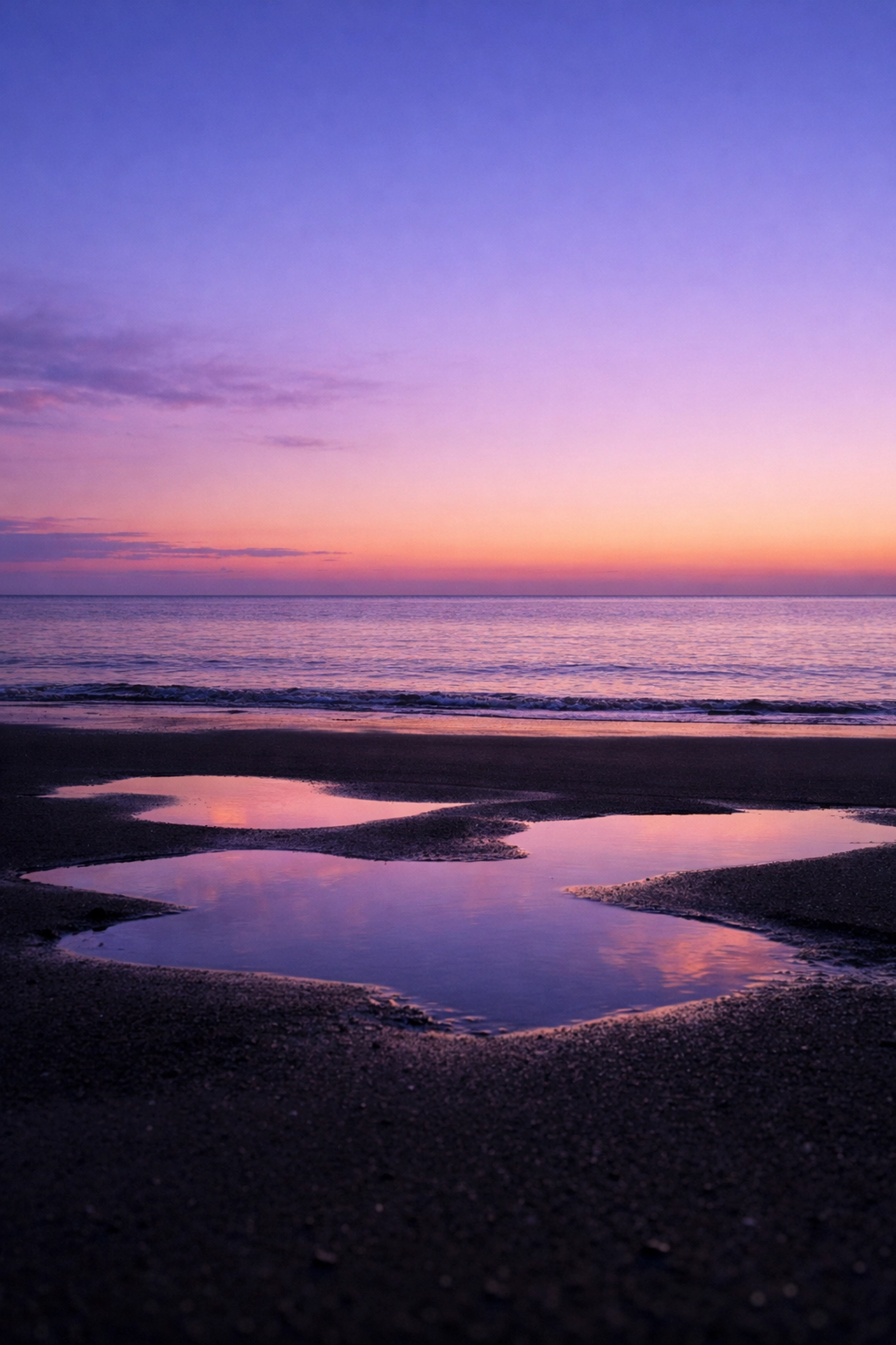Straight horizon line in ocean landscape photography at dusk with tide pool reflections.