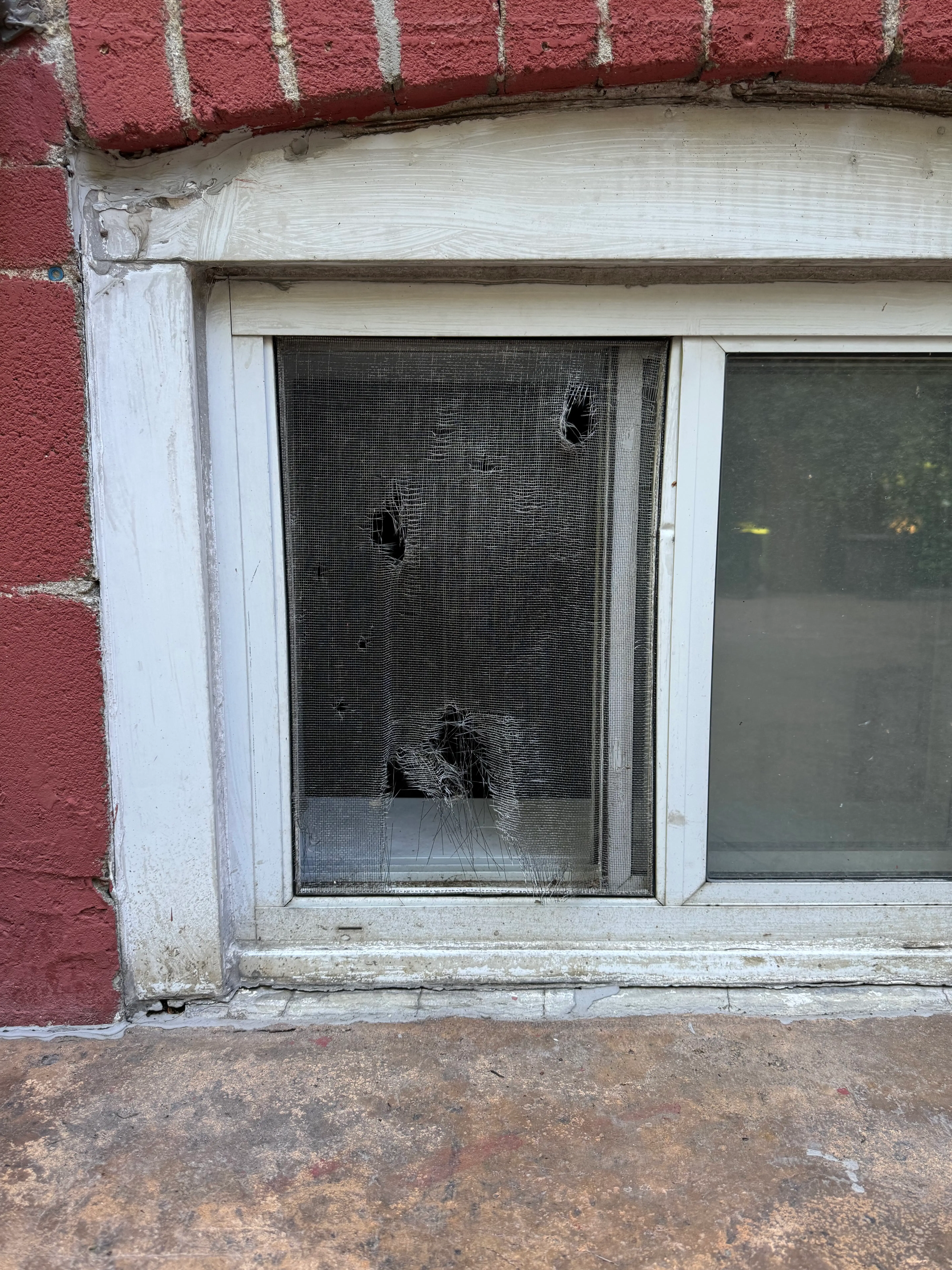 Damaged window screen with tears and holes needing repair