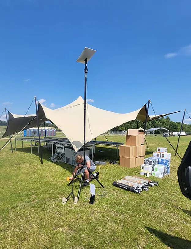Technician assembling a satellite internet uplink at an outdoor event site