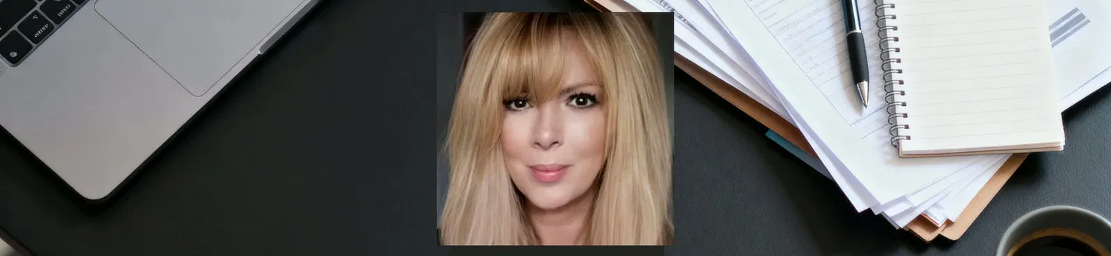 Close-up profile image of a professional workspace featuring a notepad, pen, laptop, and coffee.