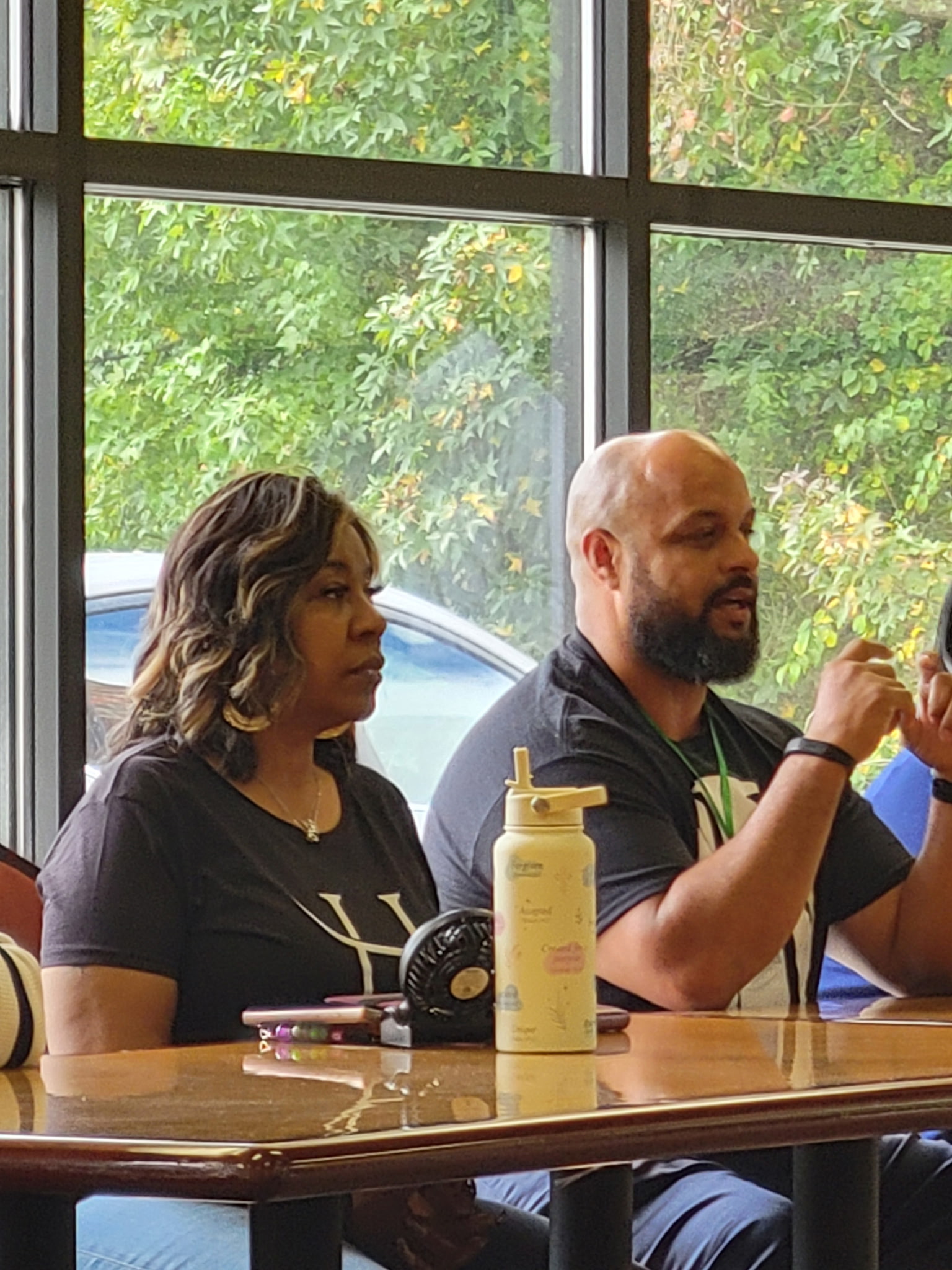Personal Growth and Relationship Workshop A man and woman sit at a table in a bright, naturally-lit room, attentively listening and discussing.