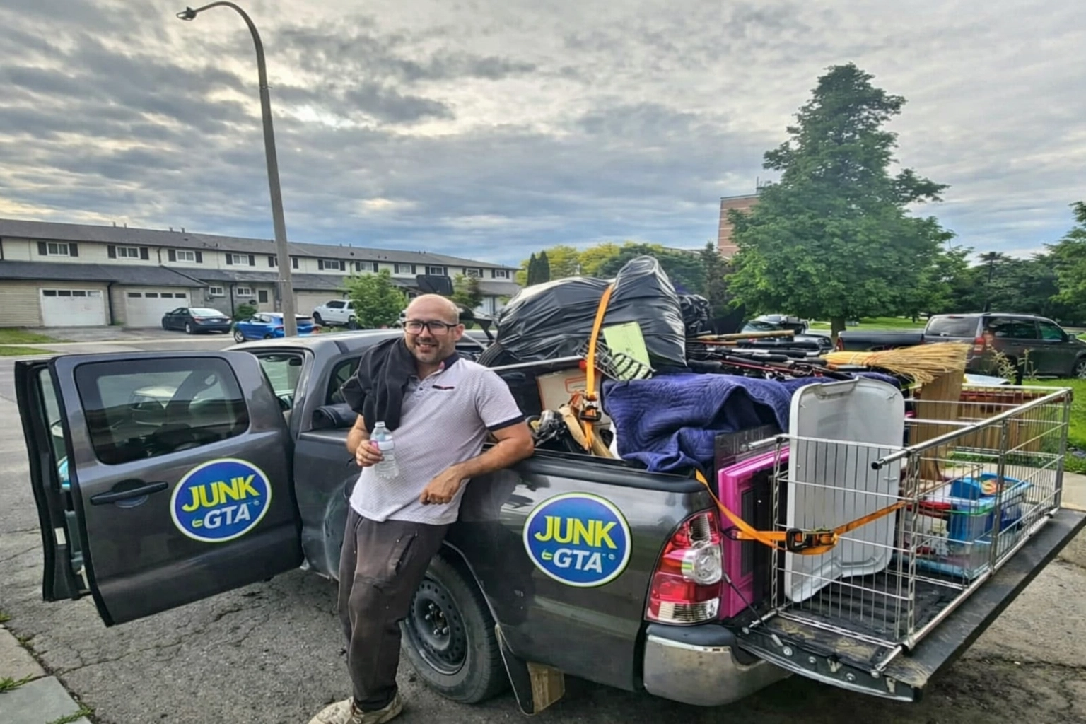 Junk GTA crew member stands beside a pickup truck loaded with various junk items