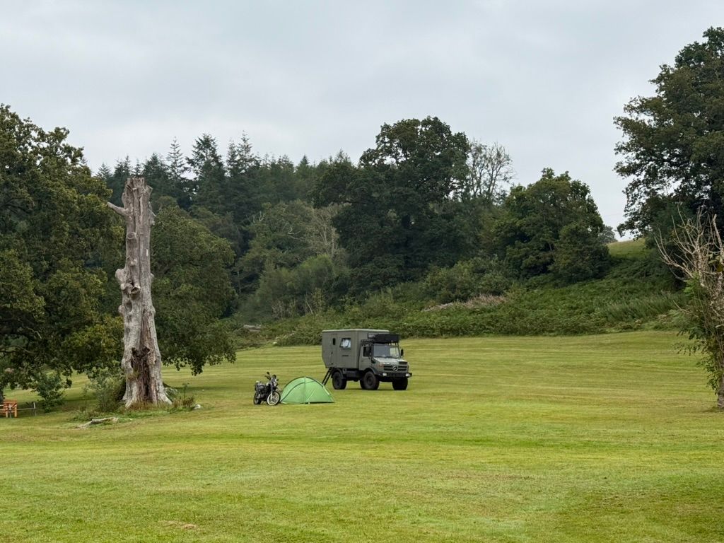 Green tent pitched beside a motorcycle and overland setup at MotoCamp Wales — a handy single-night stop on Traws Eryri.