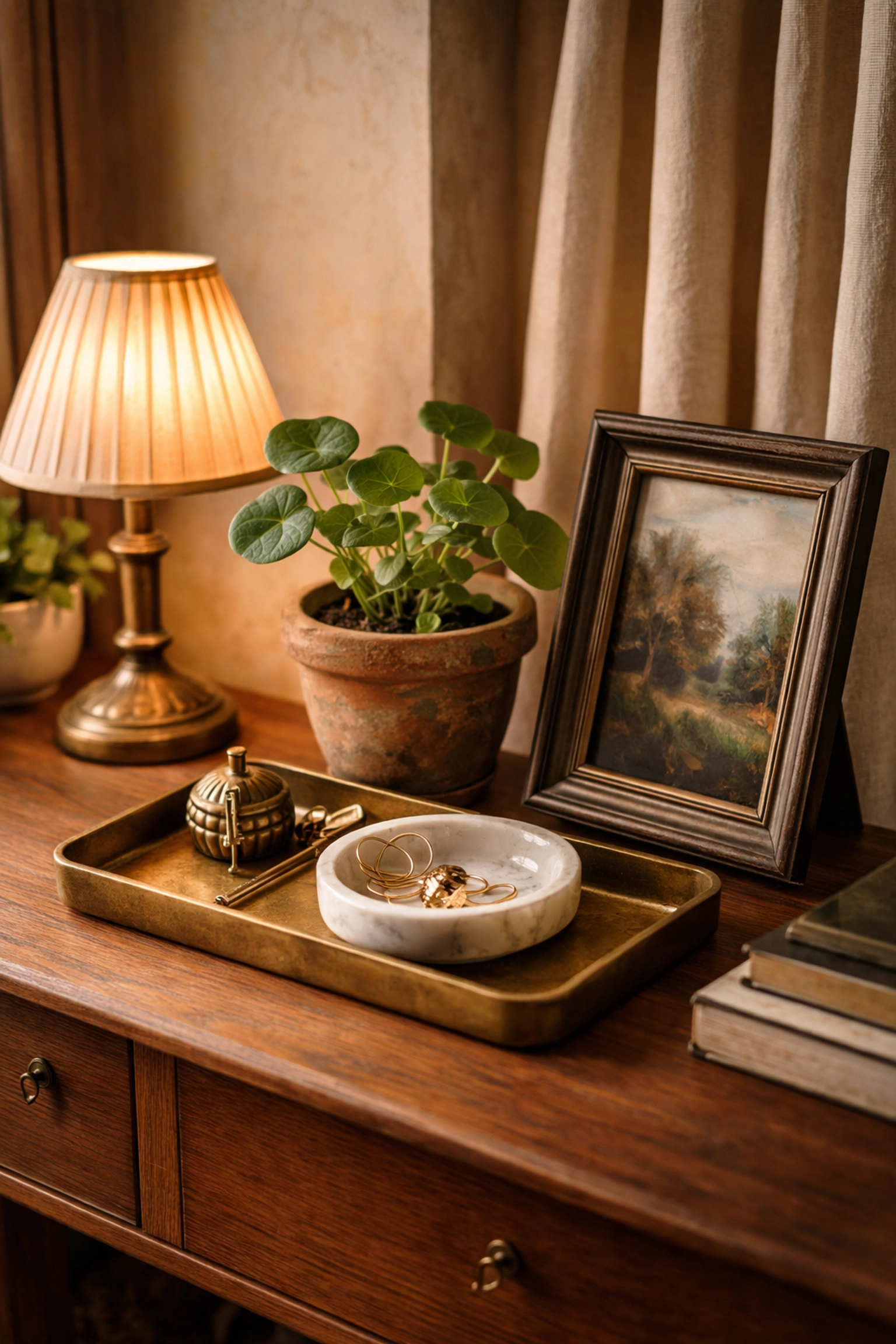 Curated vignette displaying patinated brass tray, bronze frame, and potted plant on a wooden console, exemplifying artisan home decor in a cozy setting