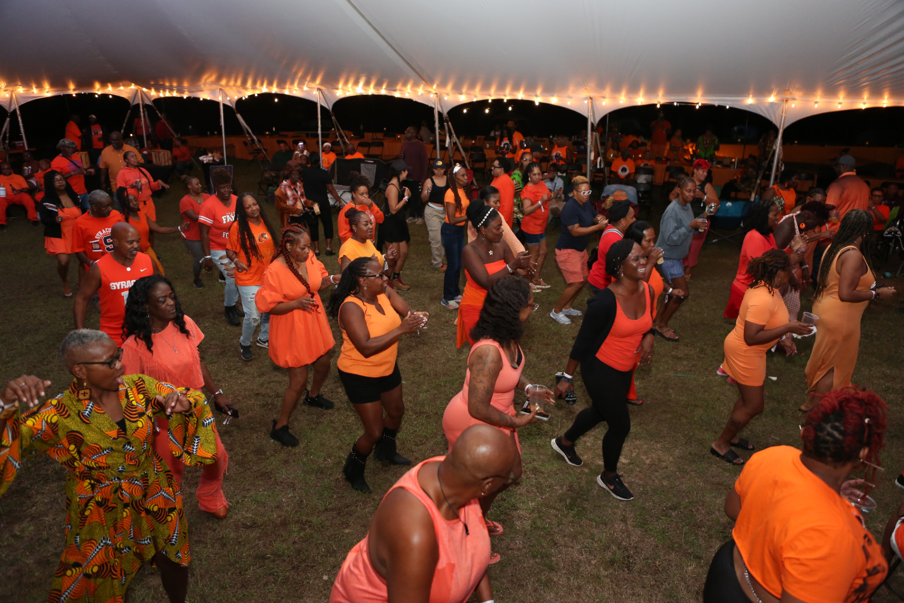 Camp Cousins line dancing together under the tent at night.