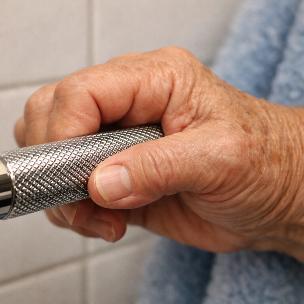 A senior's hand securely gripping a textured non-slip bathroom grab bar for better balance and support.