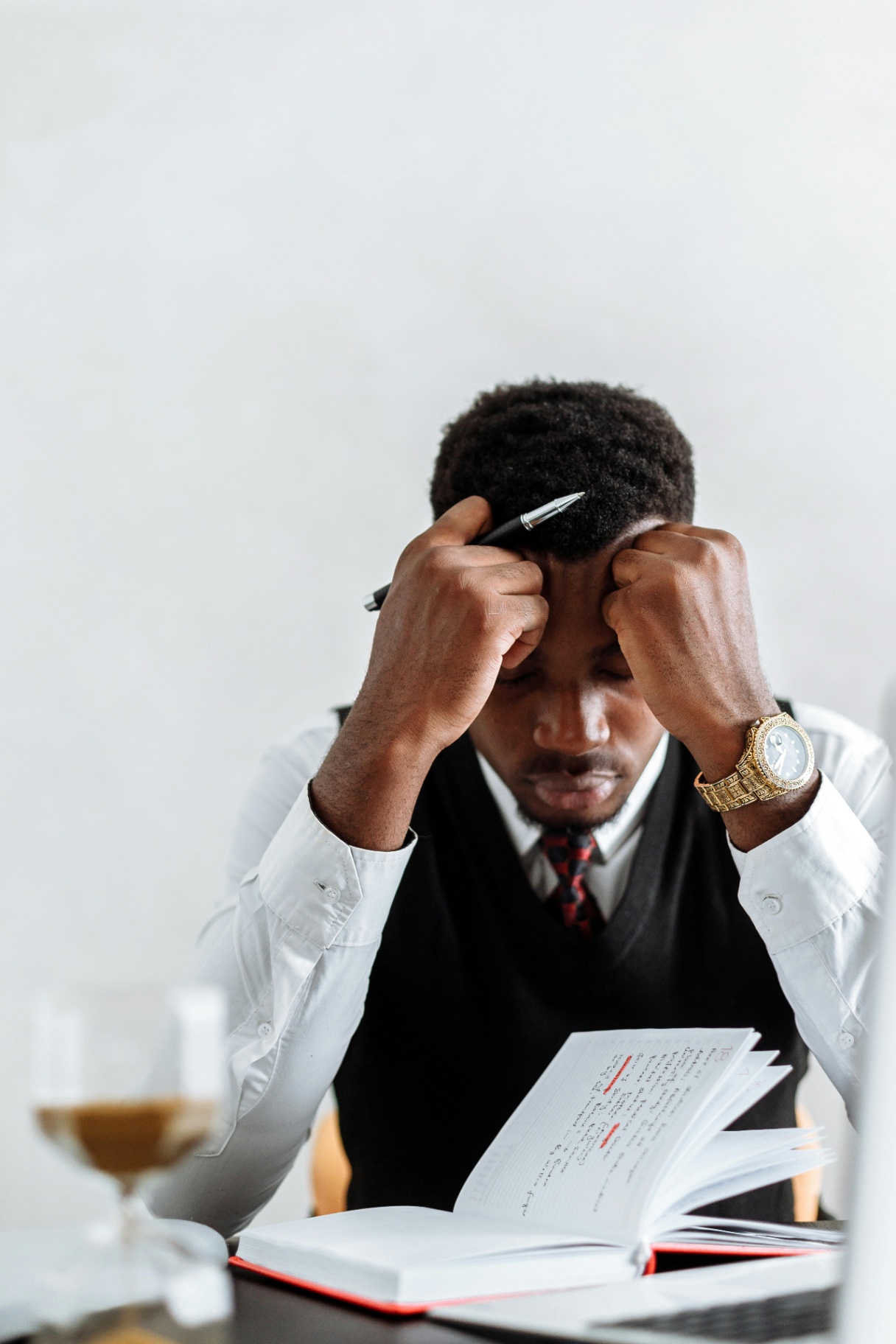 A Black man in business attire stressed at his desk