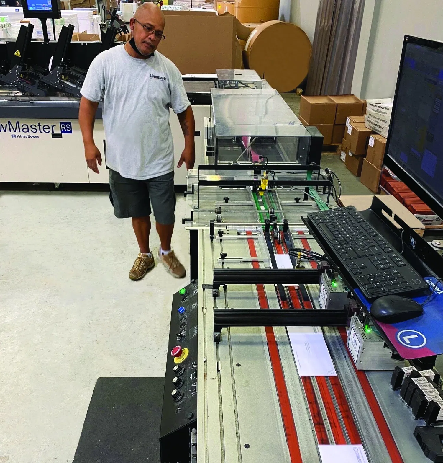 Linemark team member operating a high-speed automated mailing system for direct mail fulfillment