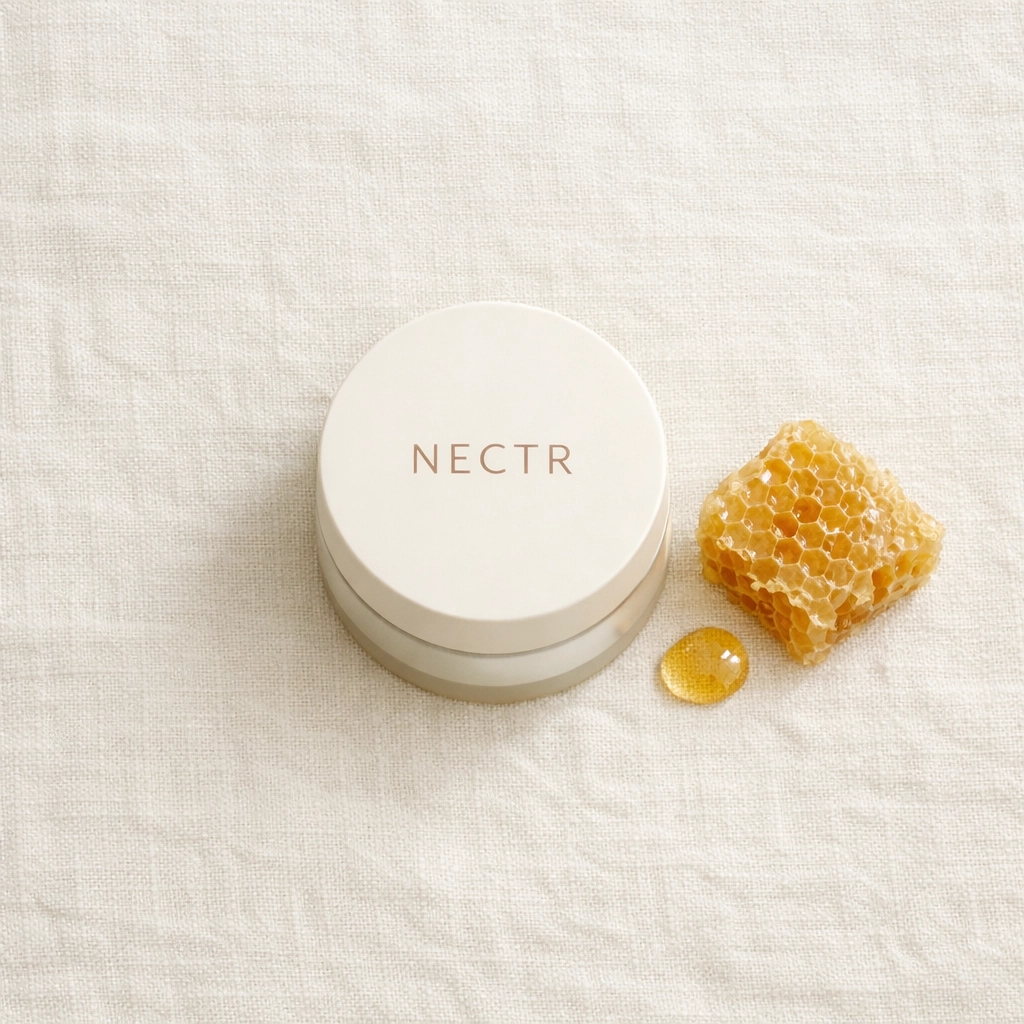 Minimalist flat lay of a NECTR jar and raw honeycomb, highlighting pure, bio-identical skin food.