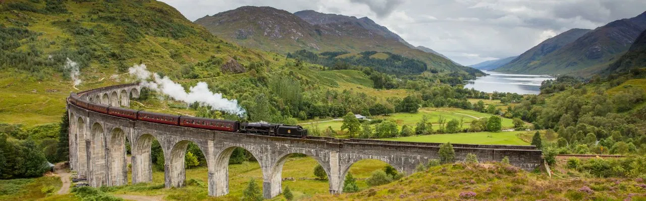 The Glenfinnan Viaduct in the Scottish Highlands with a steam train crossing