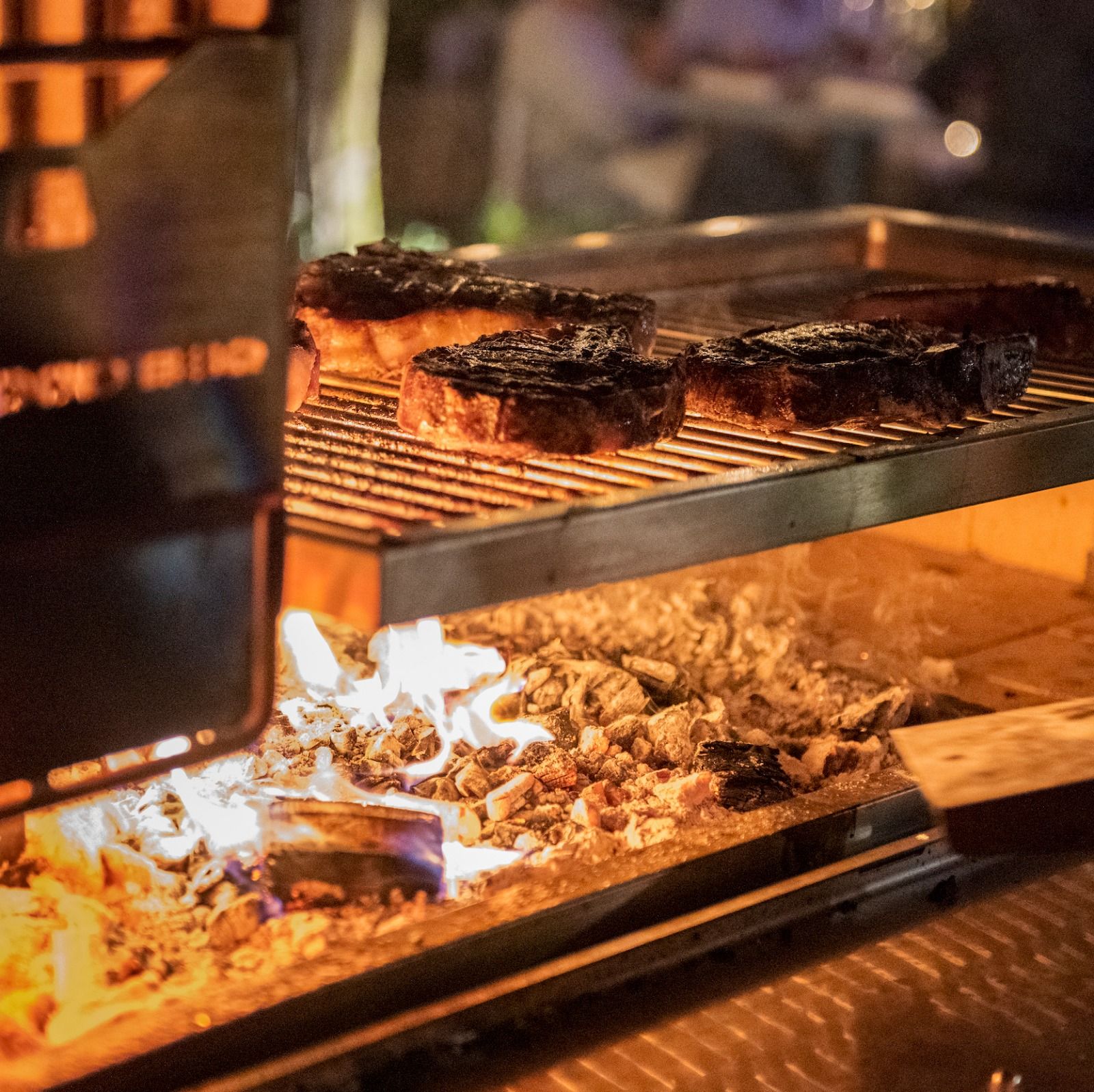 Thick-cut steaks from Meat N’ Bone being expertly grilled over open wood fire