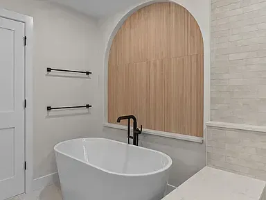 A stunning luxury bathroom remodel featuring a freestanding tub and wood accents