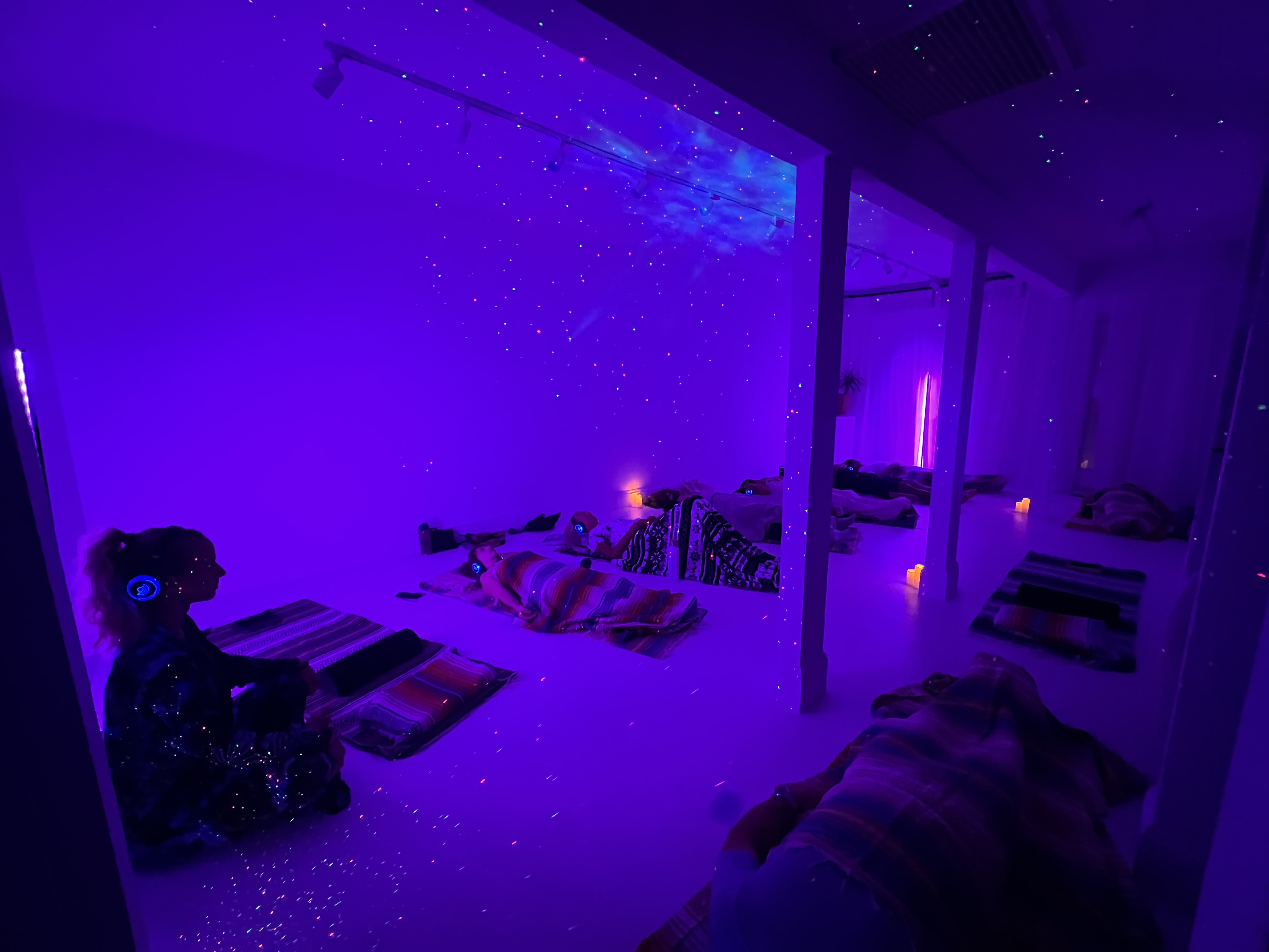 9D Breathwork Session at Vero Beach Aura Participants are lying on mats under blankets in a softly lit, purple room