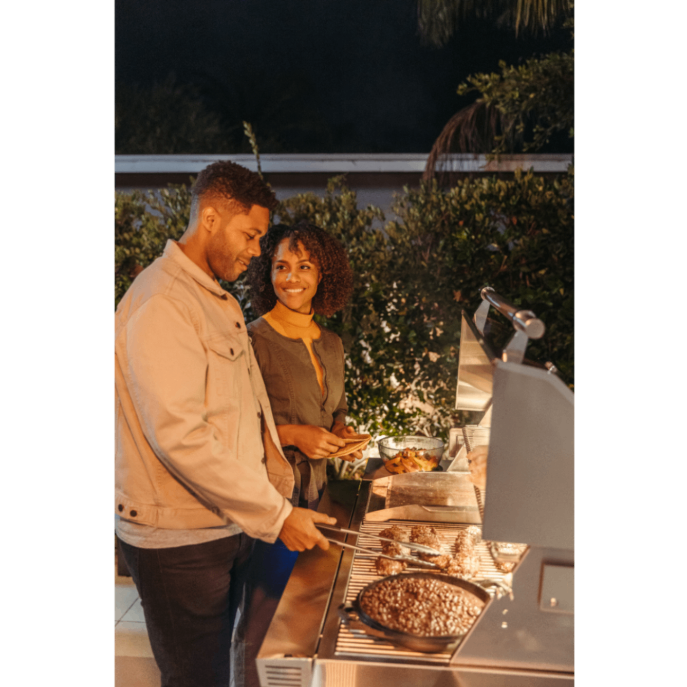 A couple grilling outdoors at night
