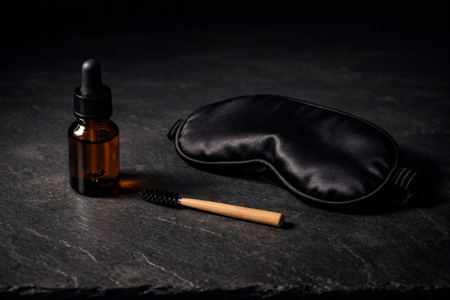 Nighttime beauty ritual featuring castor oil in a glass bottle and a bamboo lash spoolie.