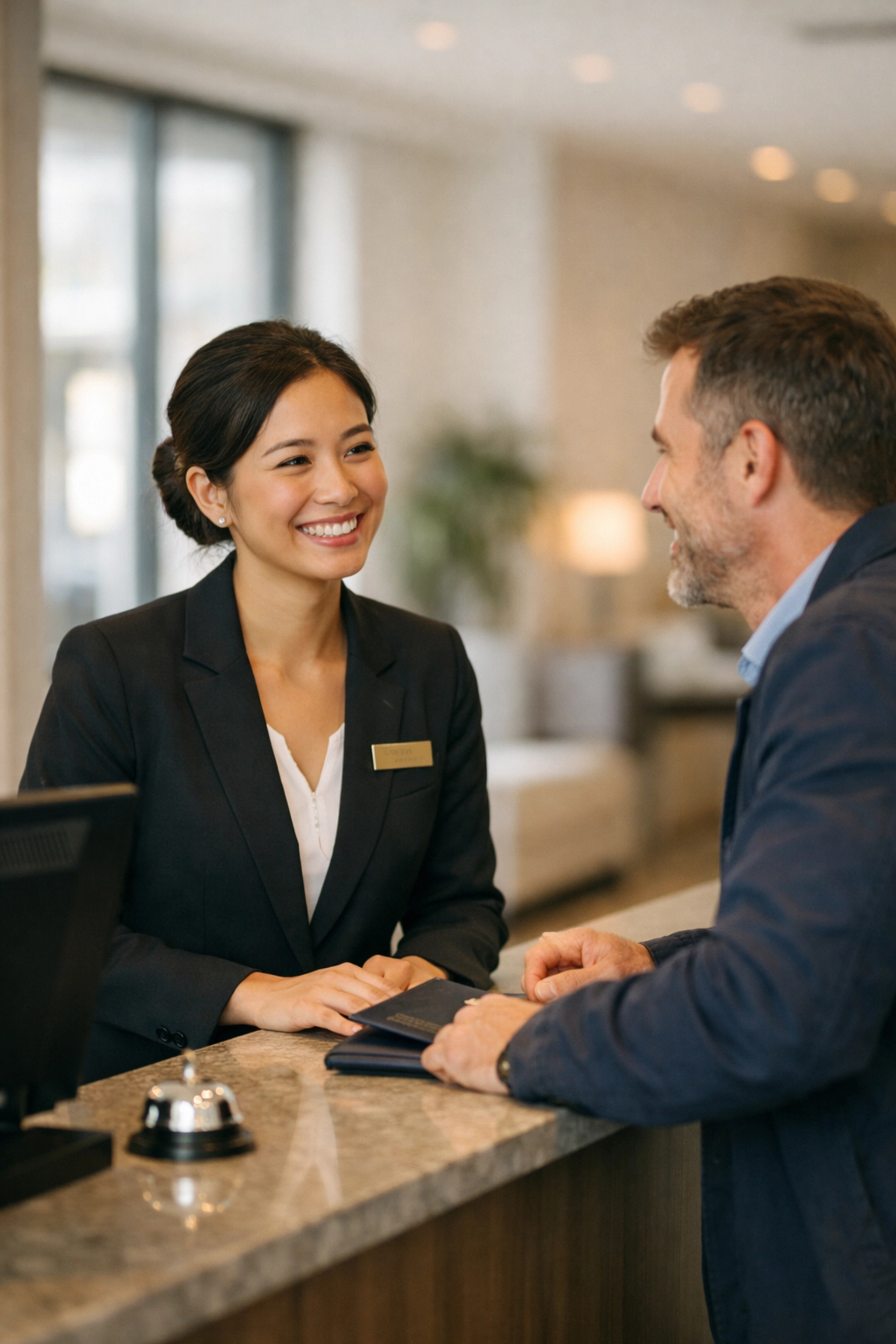 Hotel staff member engaging with guest during check-in at modern reception desk