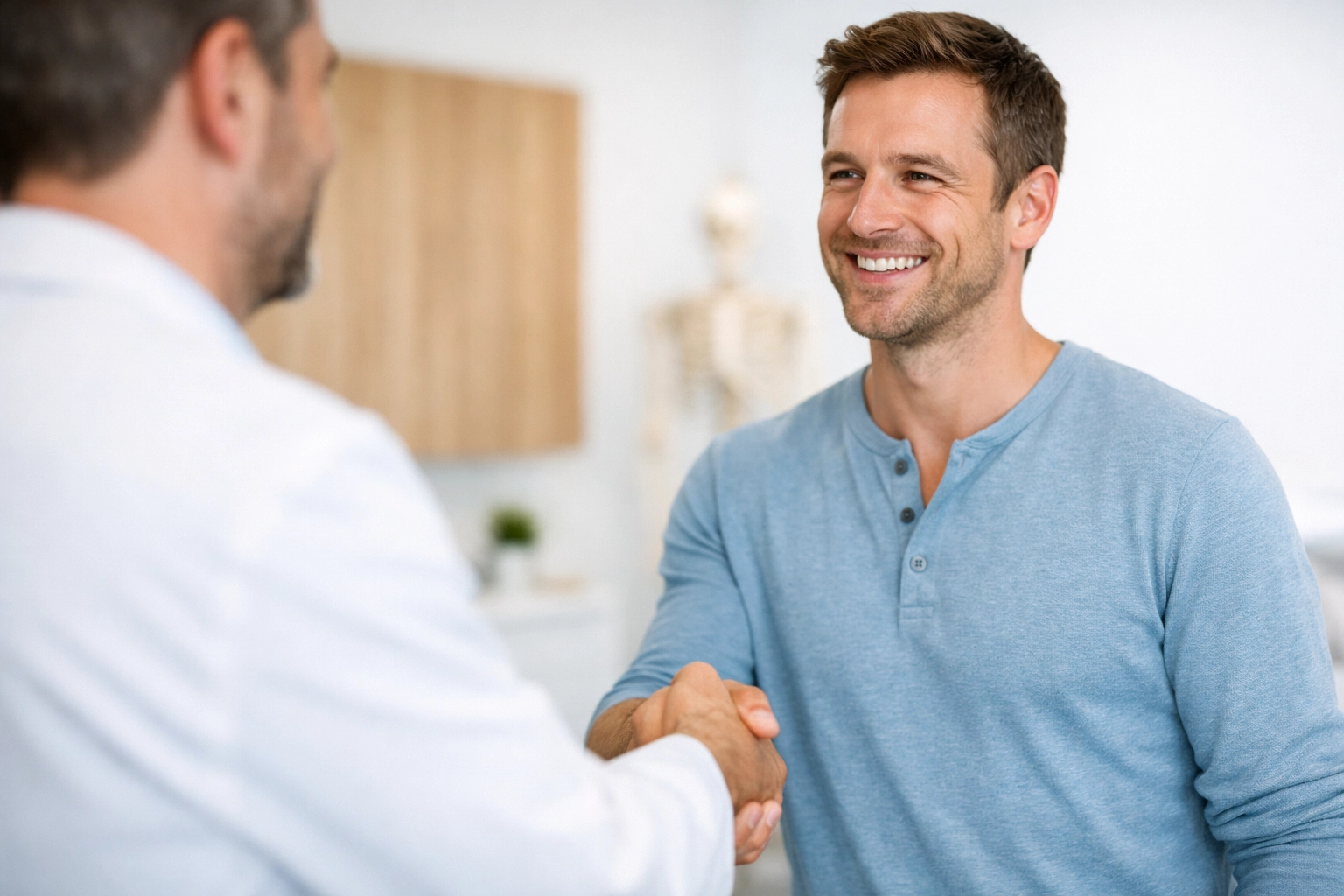 Professional chiropractor shaking hands with a patient in a modern, clinical healthcare setting.
