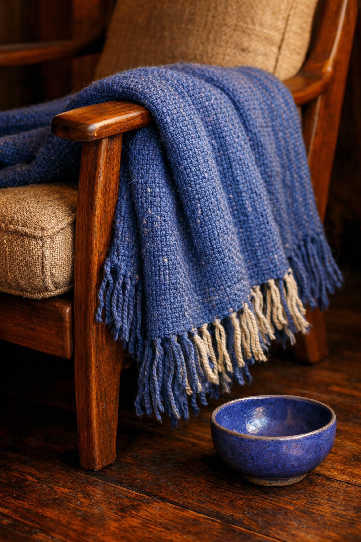 Hand-loomed cornflower blue textile throw on a wooden armchair, a sophisticated example of handcrafted home decor.