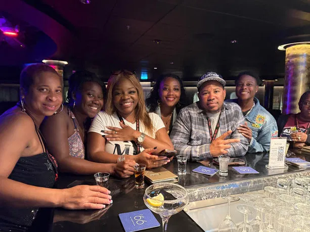 A small group of travelers shares laughter and drinks at a sleek, modern bar, capturing a moment of community connection.