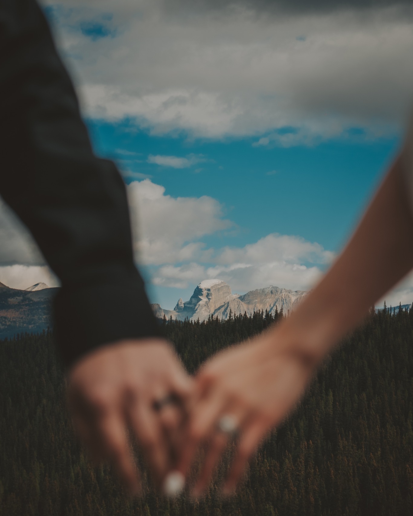 A close-up of a couple holding hands with wedding rings visible