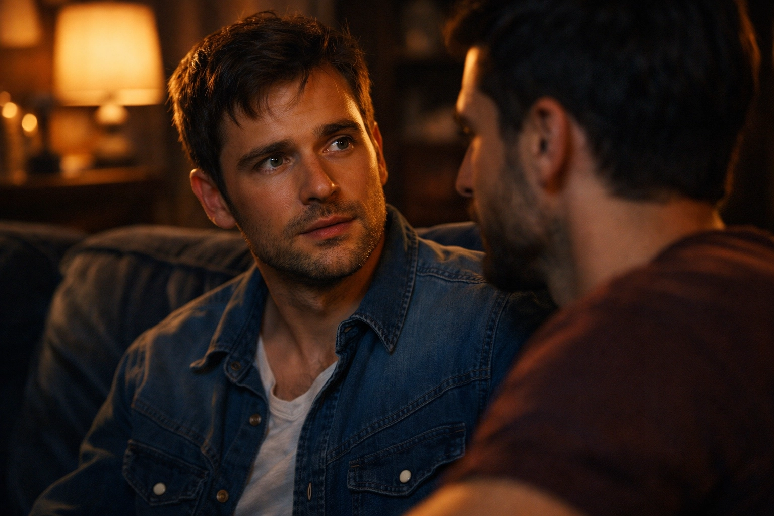 Two men on a sofa sharing a moment of realization during a bisexual awakening in an MM romance story.