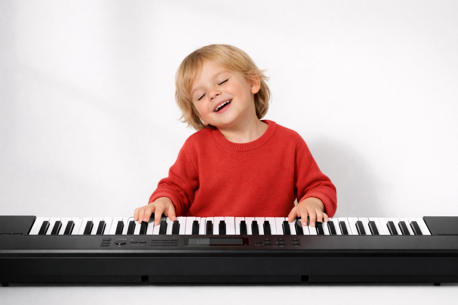 A happy child playing popular songs during beginner piano lessons on a digital keyboard.