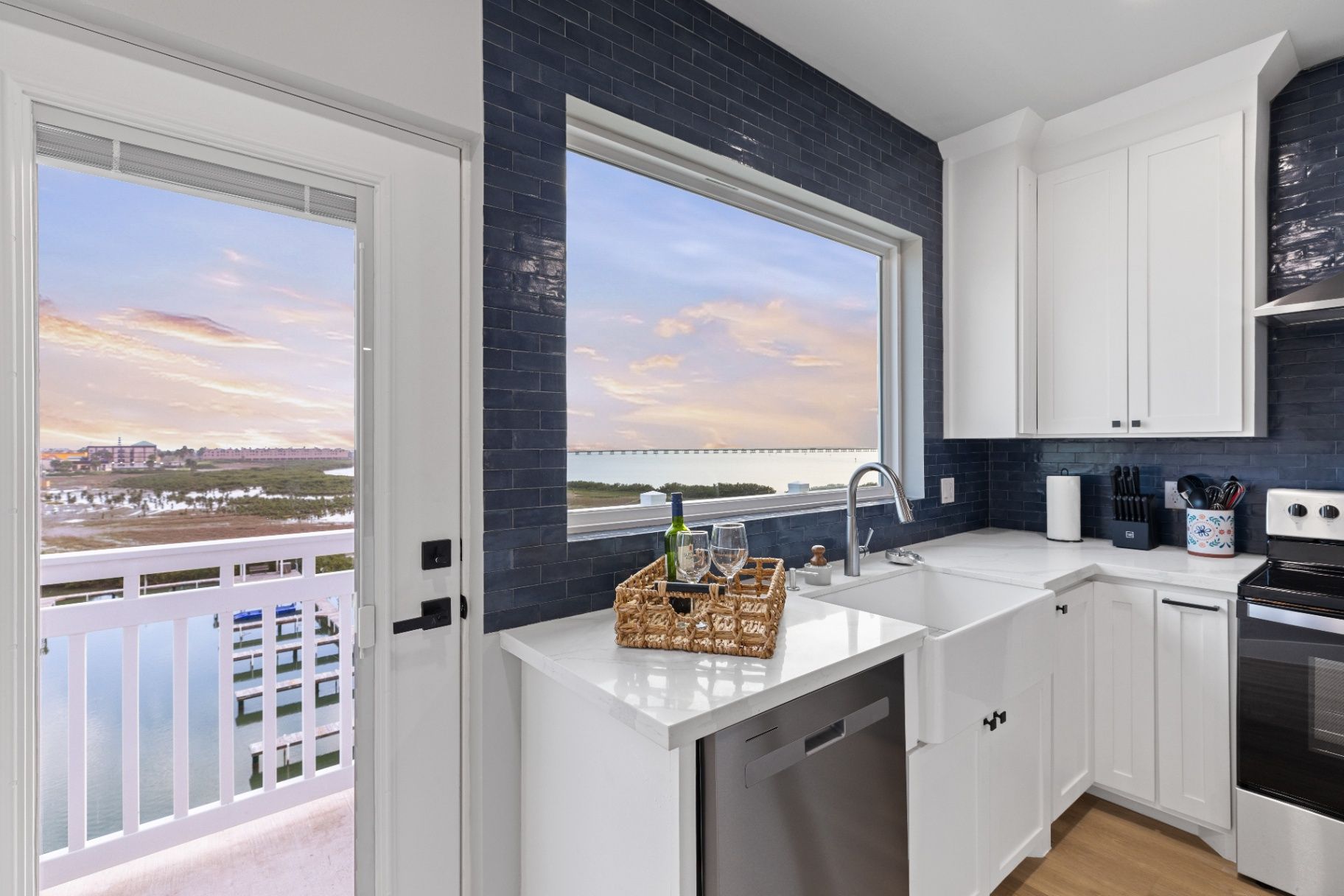 Florida Riverfront Kitchen View Modern kitchen with blue subway tile backsplash and a farmhouse sink, overlooking a marina/docks at sunset.