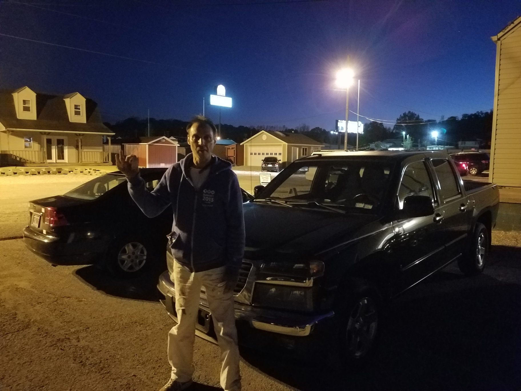 A customer stands next to a recently purchased black crew cab pickup truck