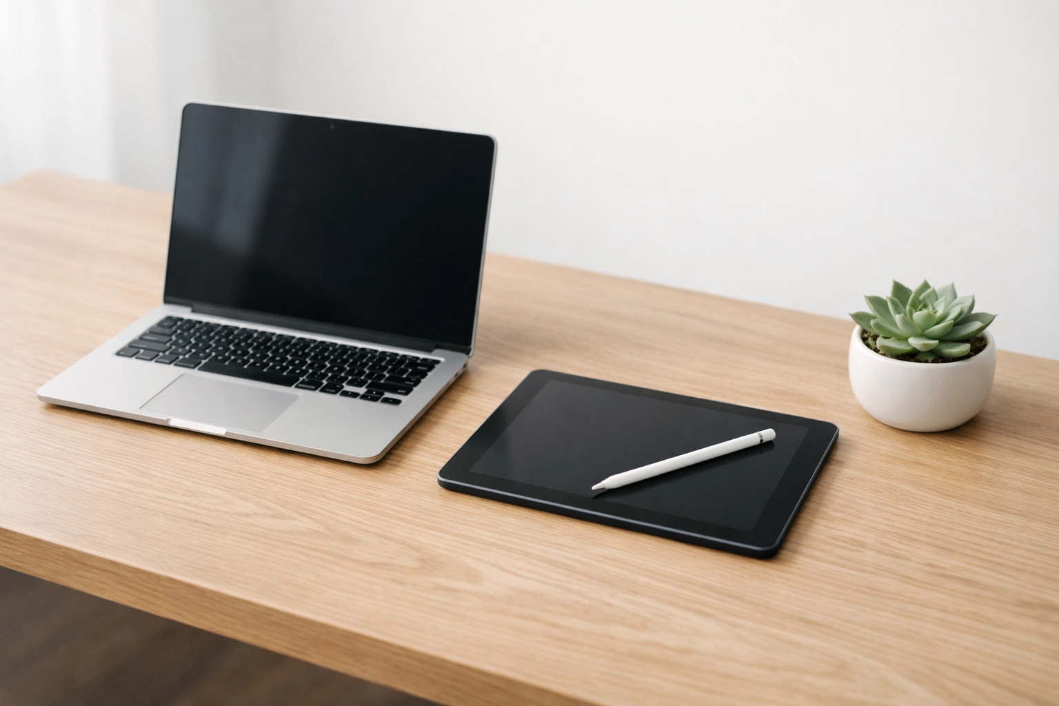 A minimalist paperless tax office setup with a modern laptop and tablet on a clean wooden desk.