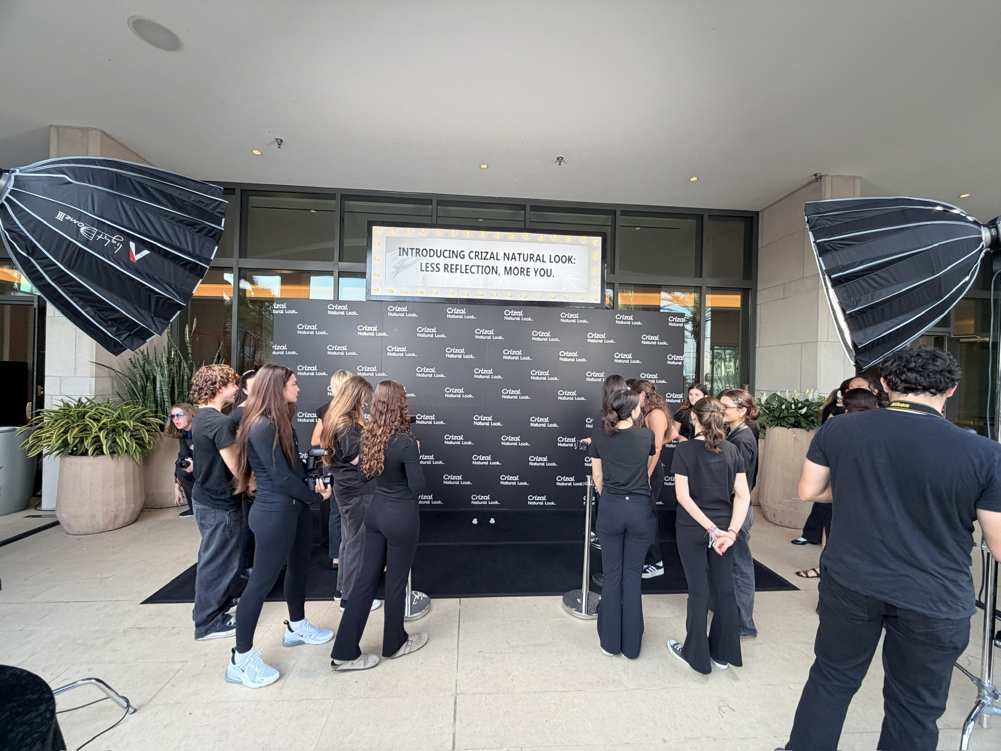 Behind-the-scenes moment on the black carpet with photographers and camera rig — controlled chaos on set.