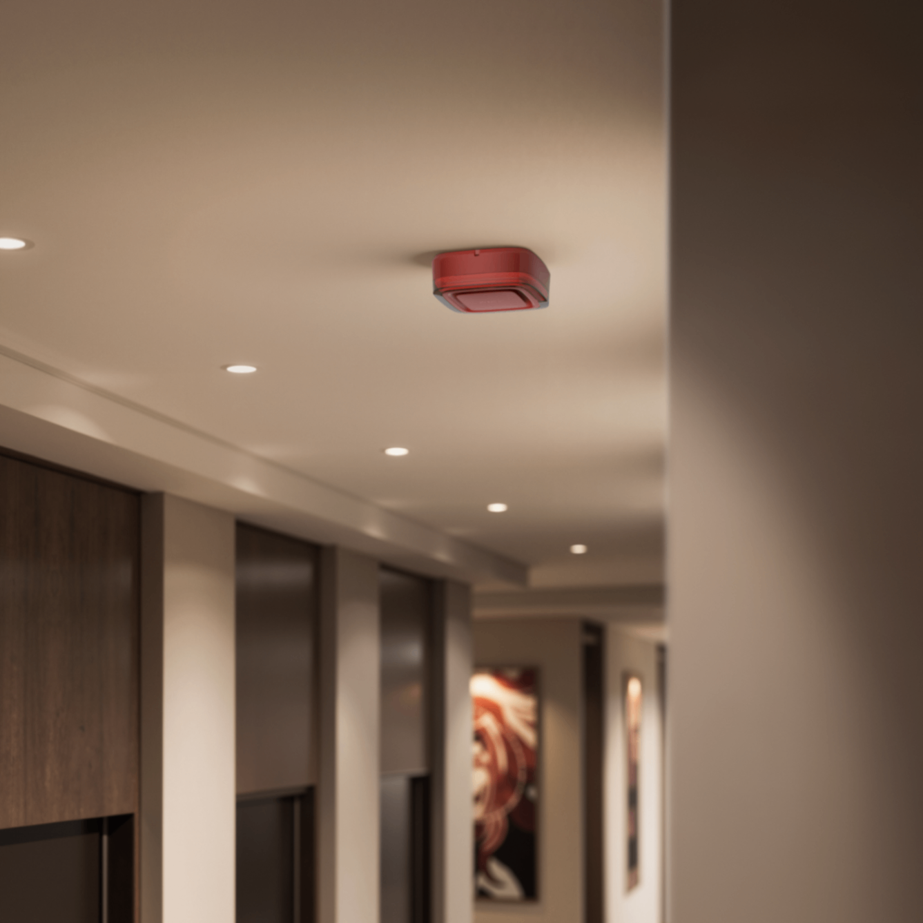 A red fire alarm sounder mounted on a modern hallway ceiling