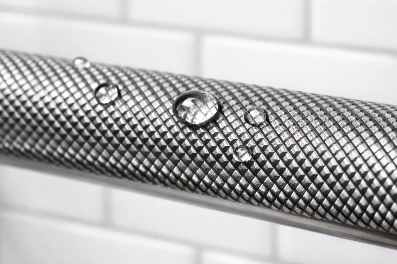 Close-up of a textured knurled stainless steel safety rail showing non-slip grip surface for bathroom safety.