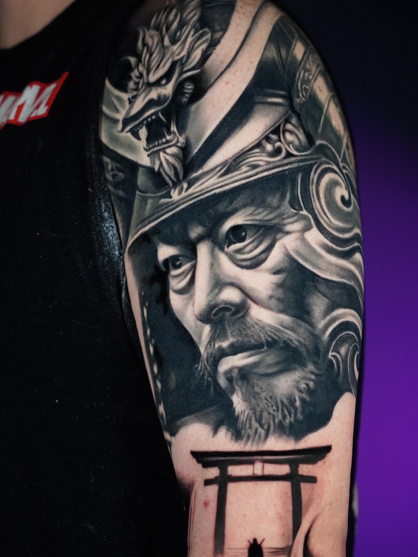 A realistic black and grey tattoo of a samurai warrior, capturing strength and heritage with skilled shading and high-contrast realism.