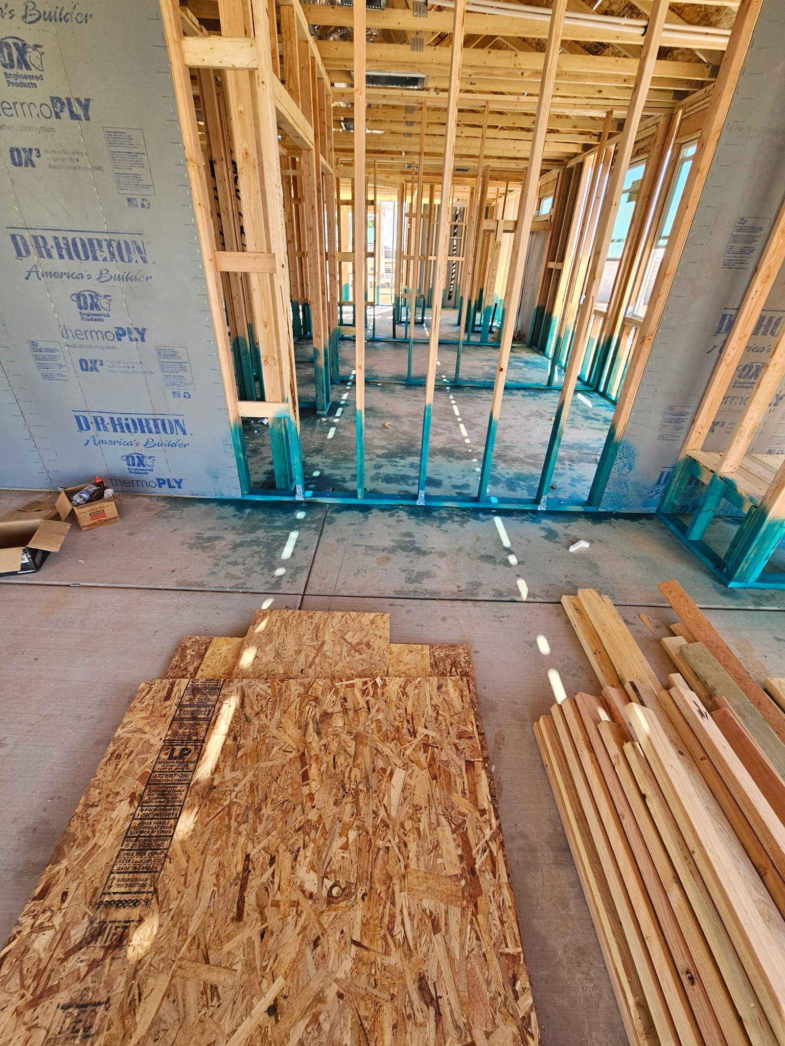 Early-stage construction of a home with exposed wood framing, visible sheathing, and insulation prep.