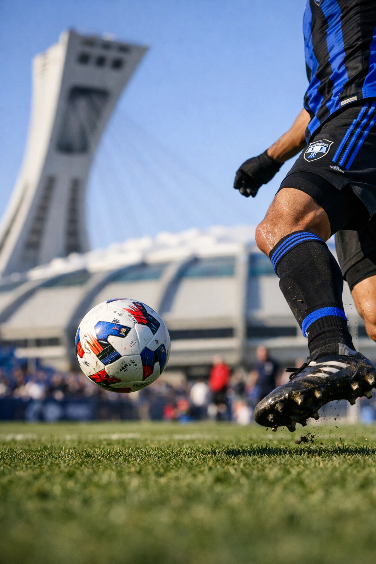 CF Montréal soccer player in action near the iconic Olympic Stadium during a March match.