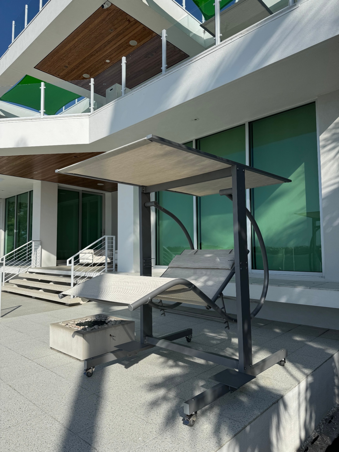 Luxury outdoor lifestyle scene featuring a David Frank Furniture Zero Gravity Swing as the centerpiece of a modern backyard setup.