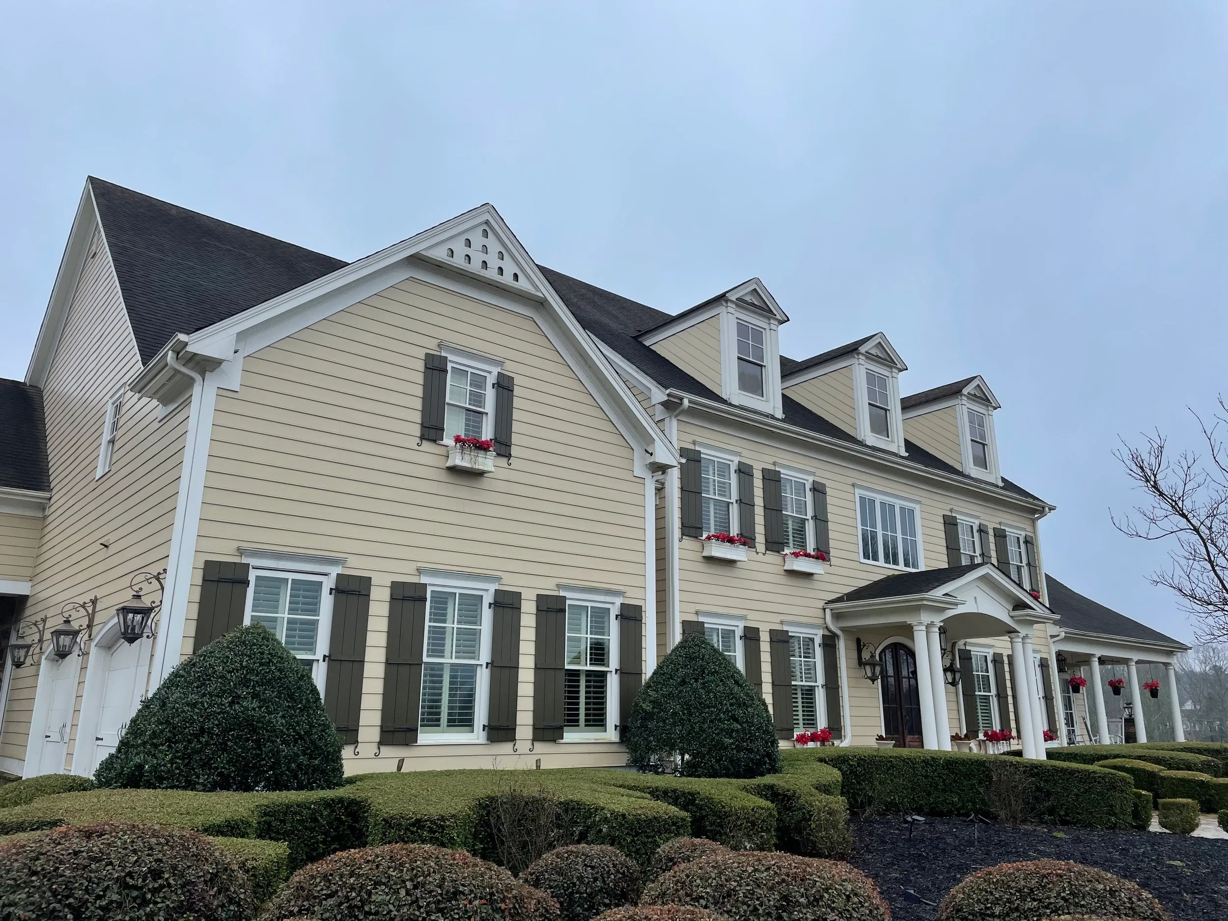 Two-story house with cream exterior and manicured landscaping