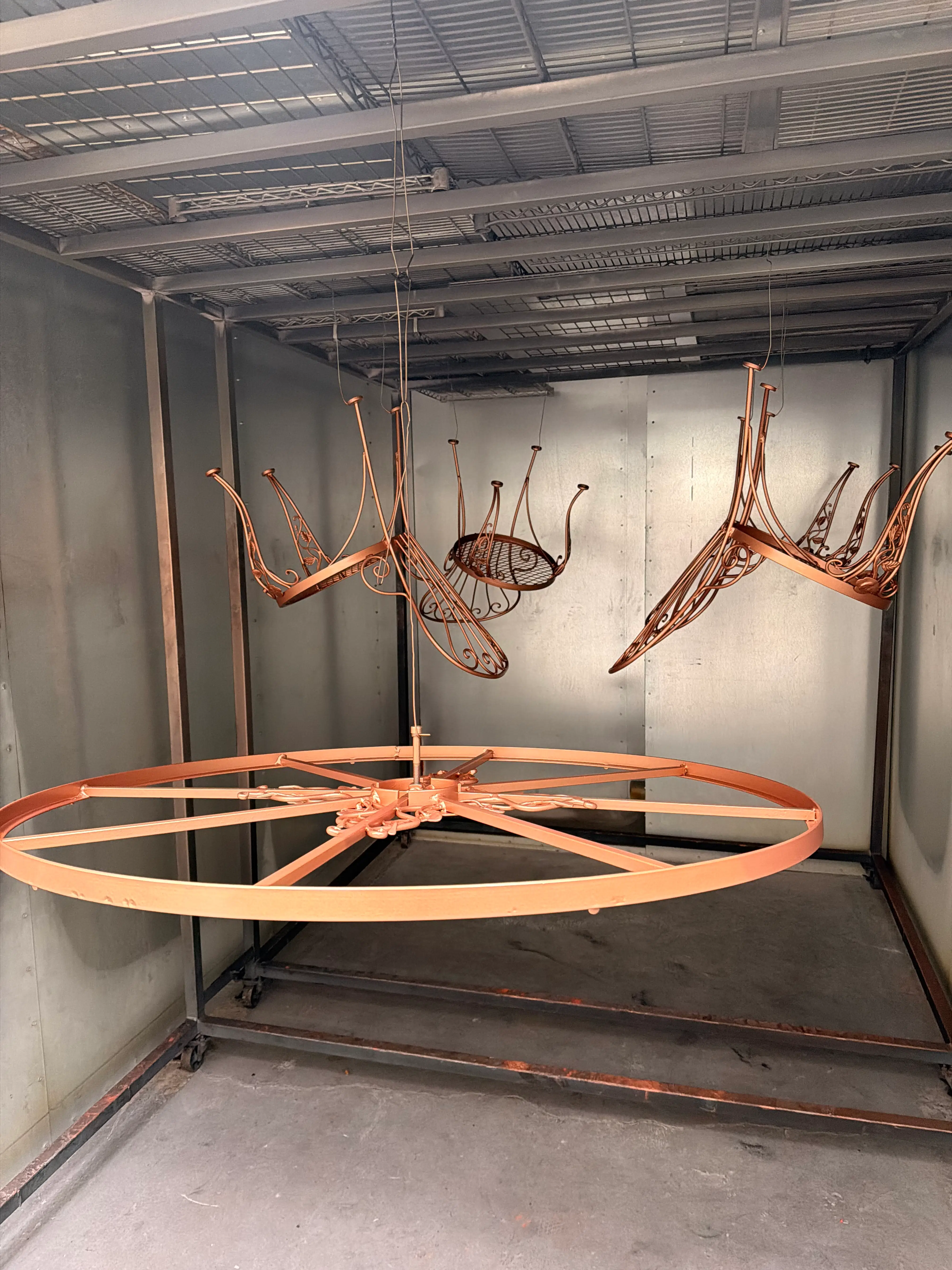 Wrought iron patio furniture and a large decorative wheel in copper finish