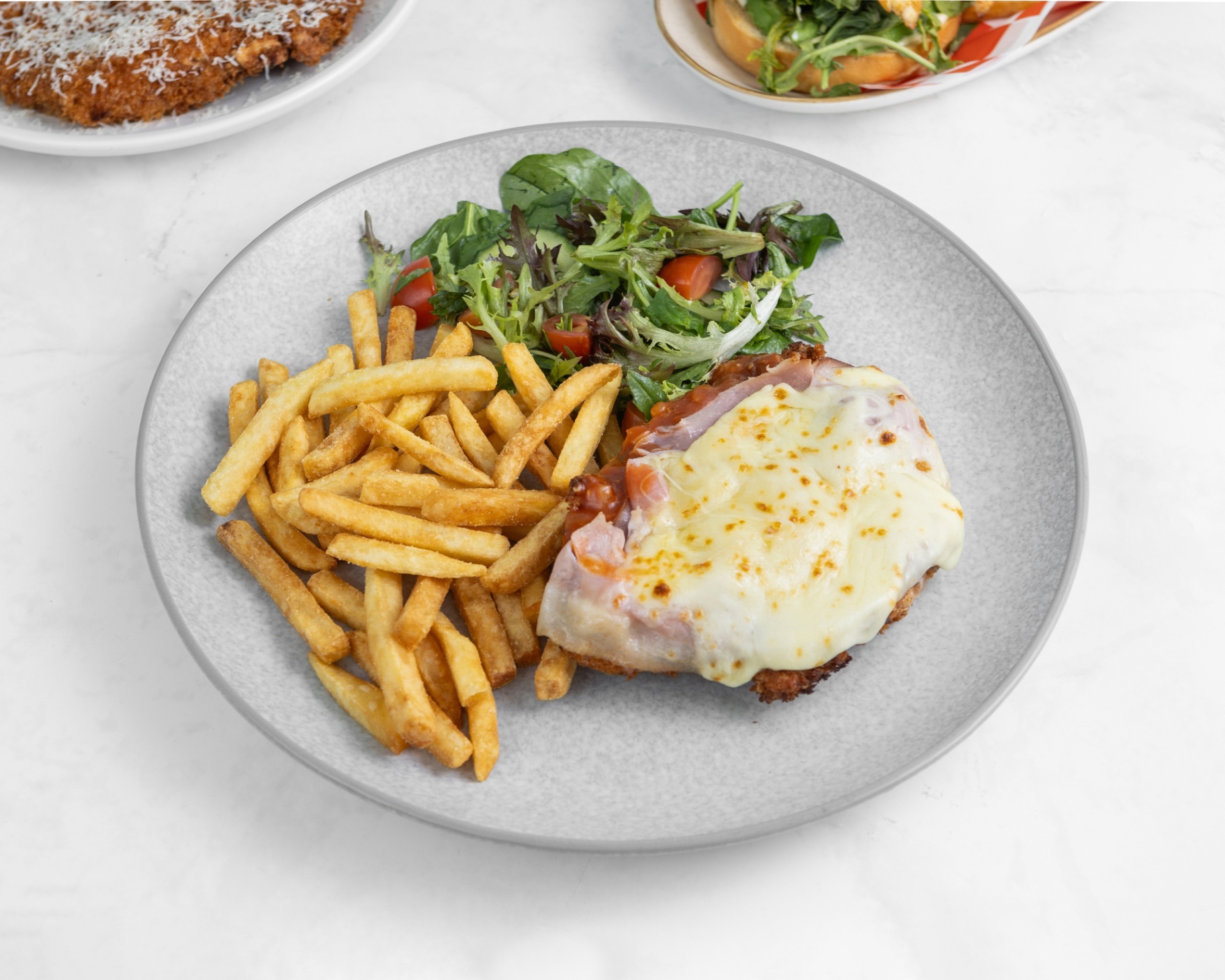 Classic chicken parmigiana served with golden fries and salad