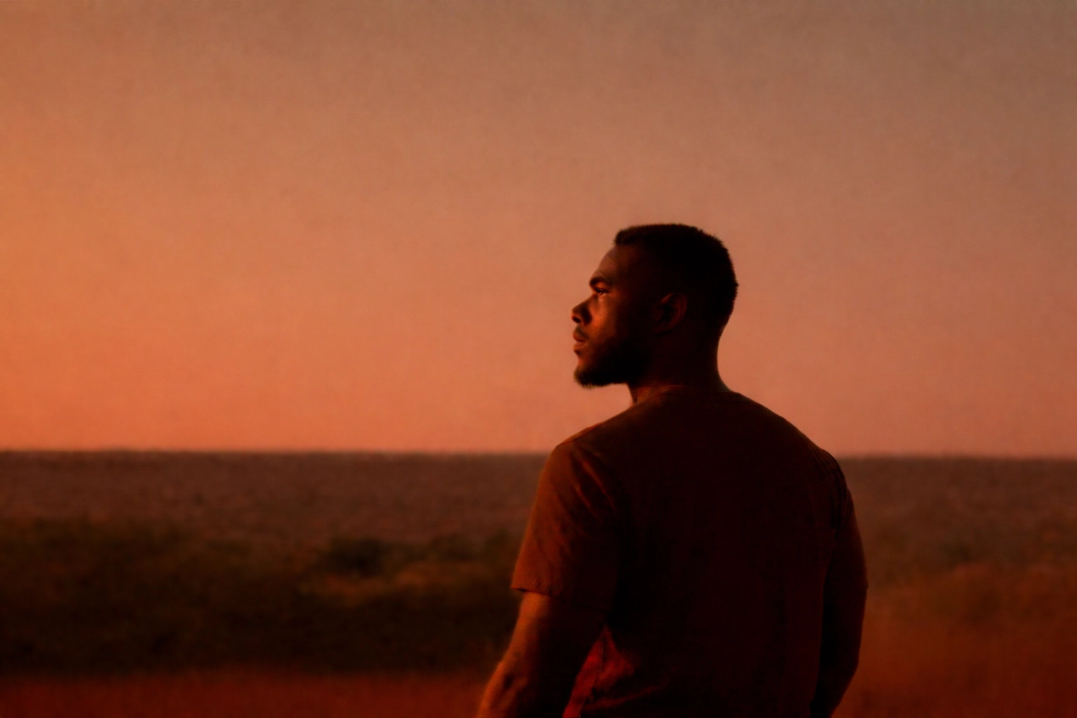 The Invisible Burden A Black man stands outside at sunset, looking thoughtful, as the text discusses mental health and the social realities faced by Black men. The image promotes awareness of the unique mental health challenges Black men encounter and highlights 'The Invisible Burden' by Rodrego Way, LPC-S, LCDC, as a clinic dedicated to supporting these needs.