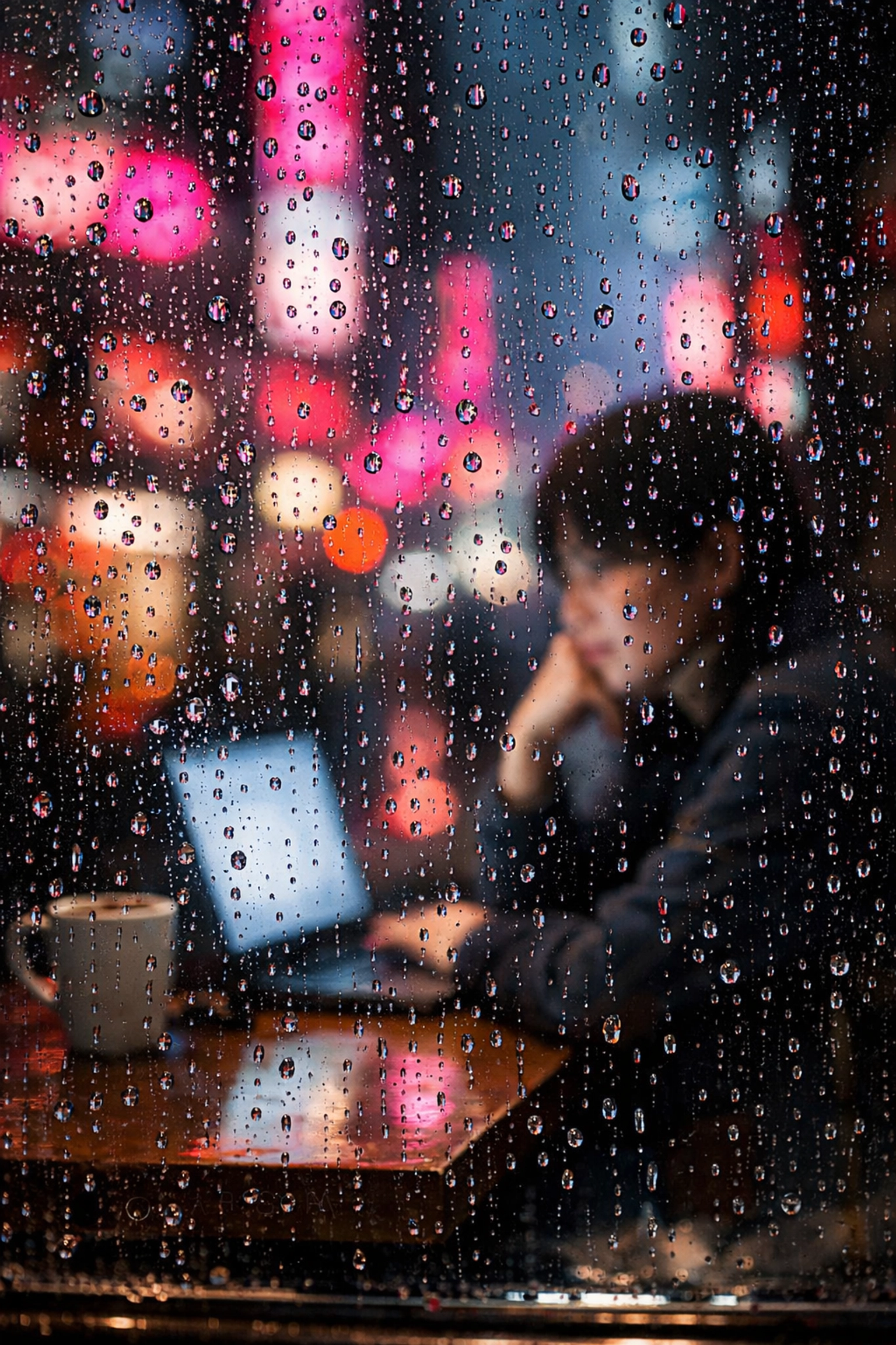 Creative street photography ideas using portrait photography techniques through a rainy window with neon reflections.