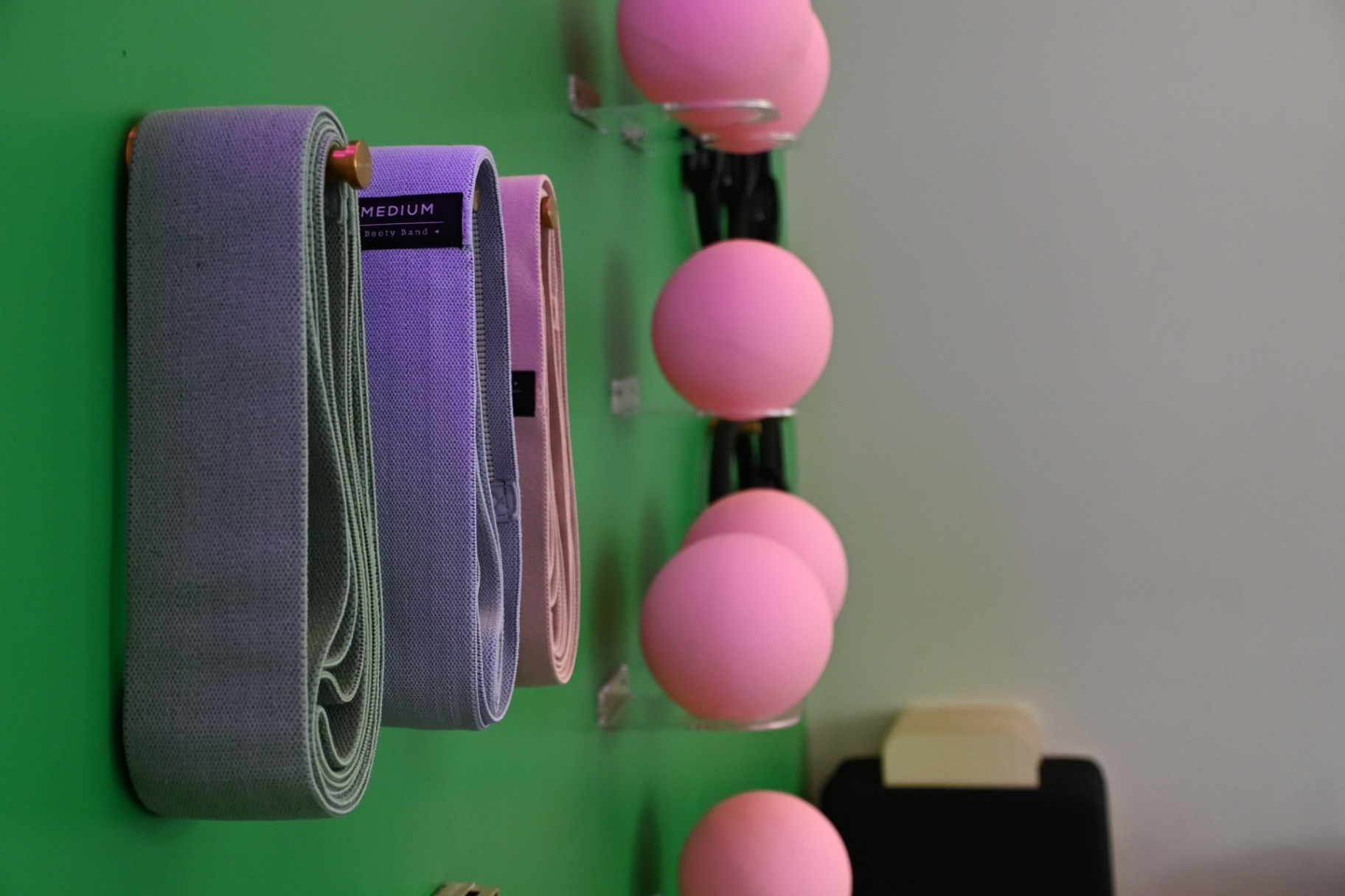 Resistance booty bands and pink Pilates balls on wall rack