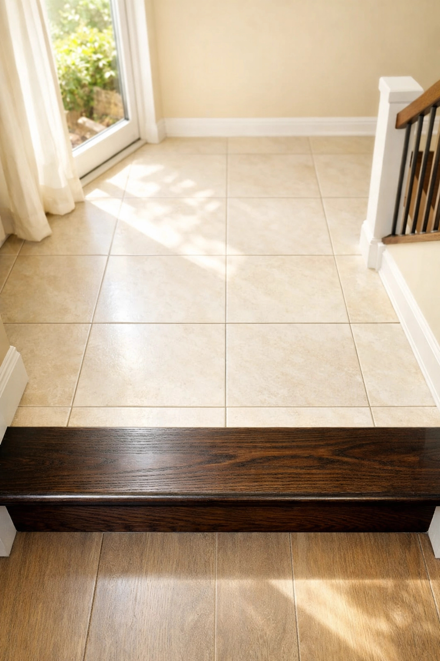 High-contrast dark wood stair edge against a light landing floor to clearly mark the bottom step and prevent falls.